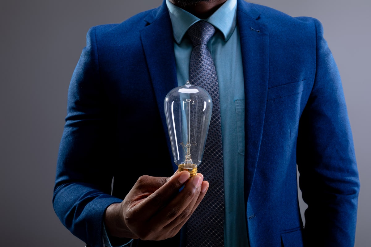 mid-section-of-businessman-holding-light-bulb-agai-2023-11-27-05-36-52-utc-min